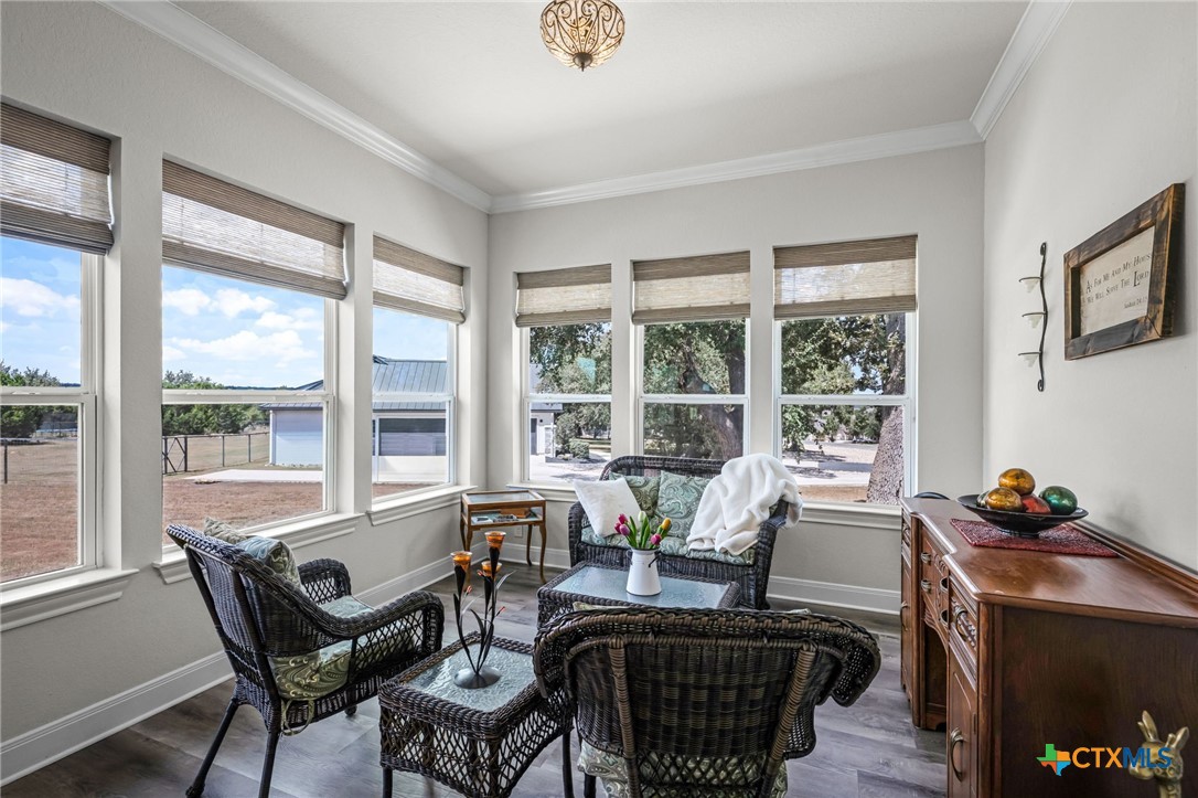 Furnished sitting room with wicker seating and wide windows overlooking a fenced yard.