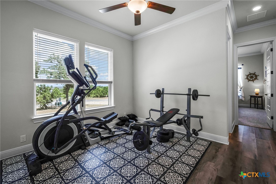 Home gym with an elliptical, weight bench, and barbell on a patterned rug.