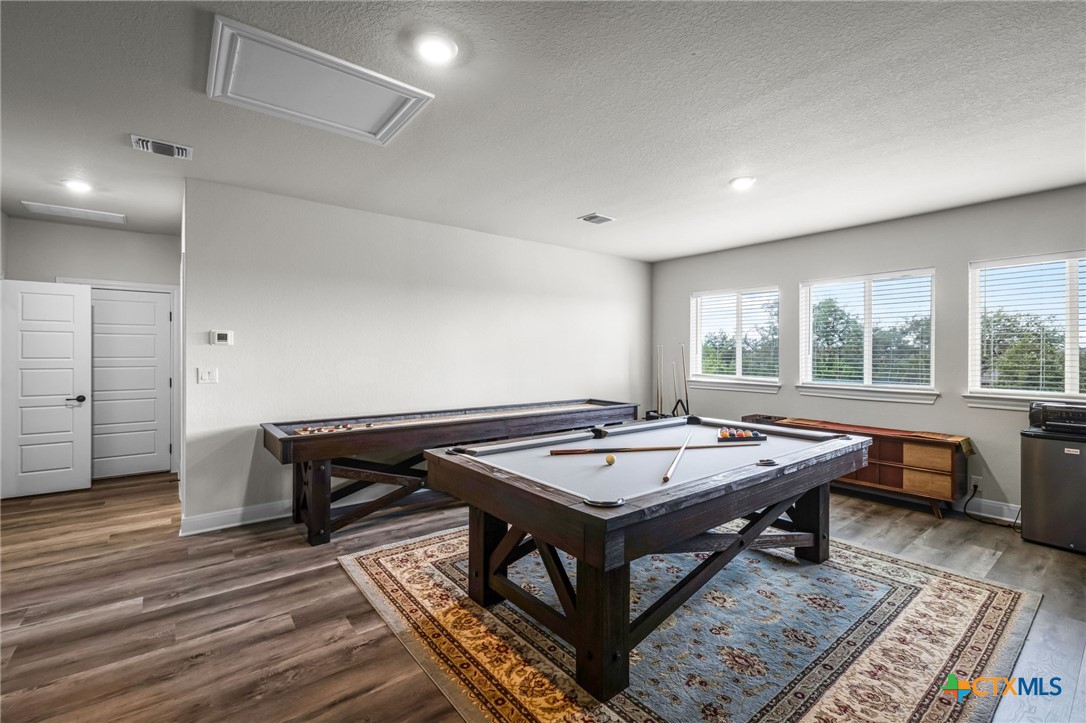 Game room with a pool table and shuffleboard table on wood-look flooring.