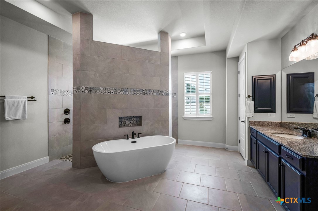 Spacious bathroom with a freestanding soaking tub, tiled shower, and dark blue vanity.