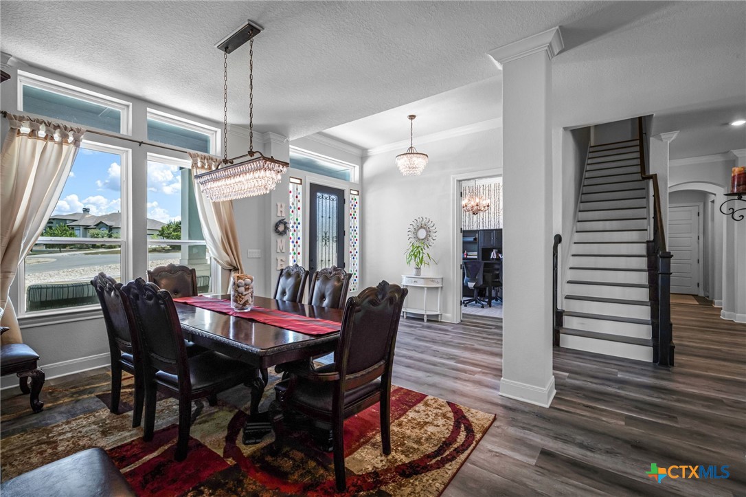 Dining room with a dark wood table, leather chairs, crystal chandelier, and large windows.