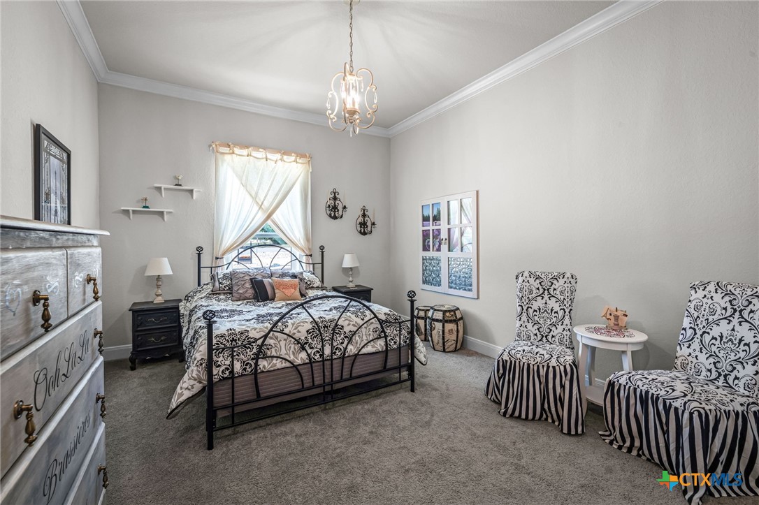 Furnished bedroom with a black metal bed, patterned bedding, matching chairs, and a tall curtained window.