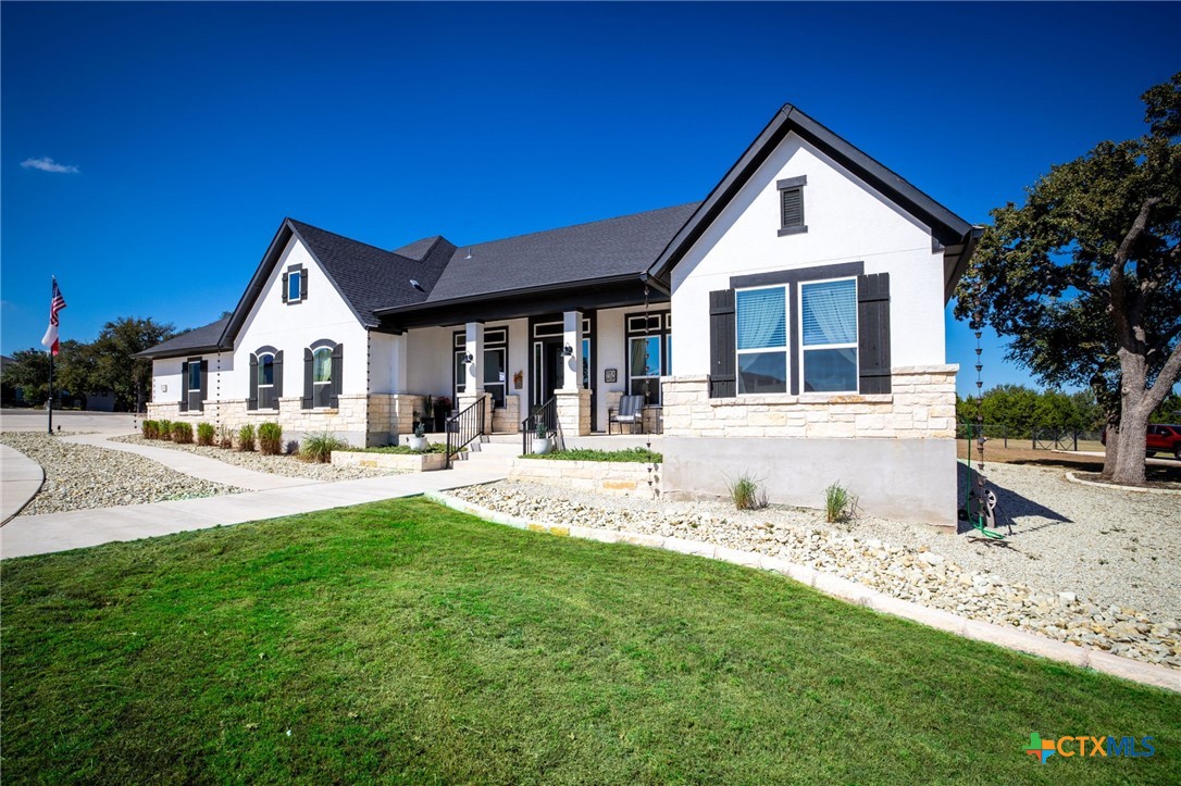 Single-story white house with stone accents, a covered porch, and a broad green lawn.
