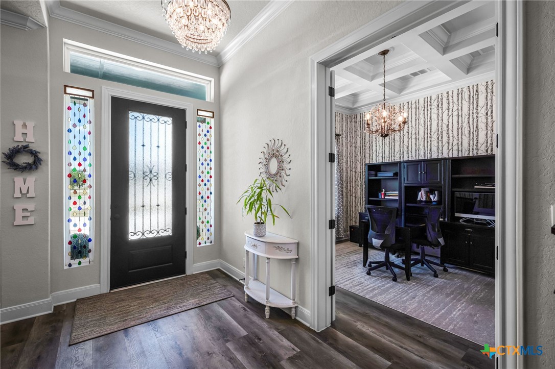 Foyer with a black front door and colorful stained-glass sidelights, opening to a built-in home office.