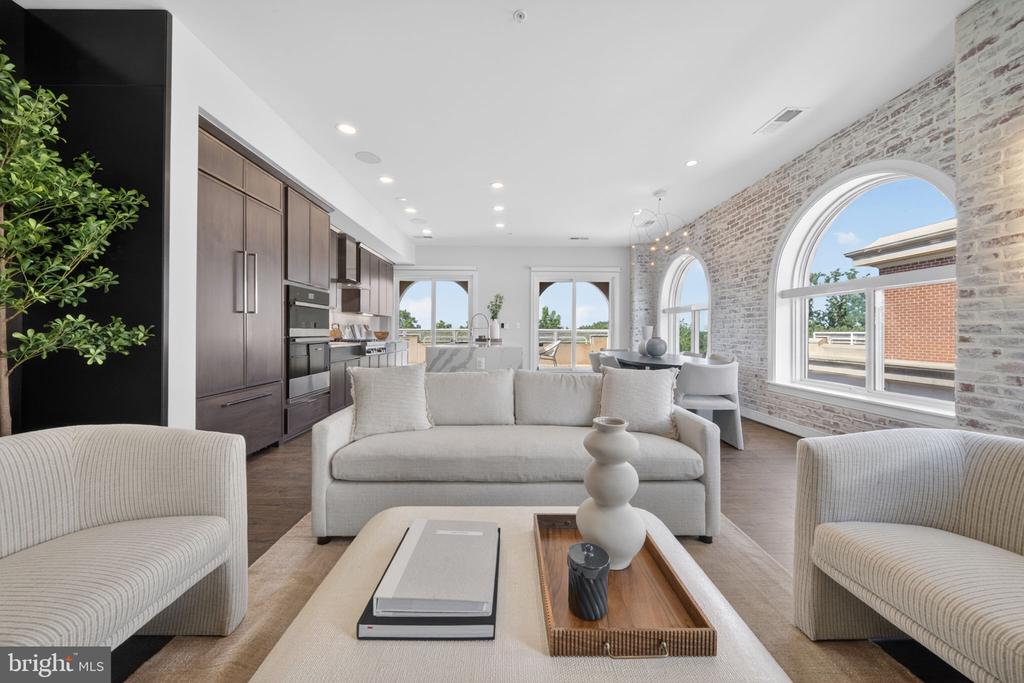 Open-plan living room with arched windows, exposed brick, and a dark wood kitchen.