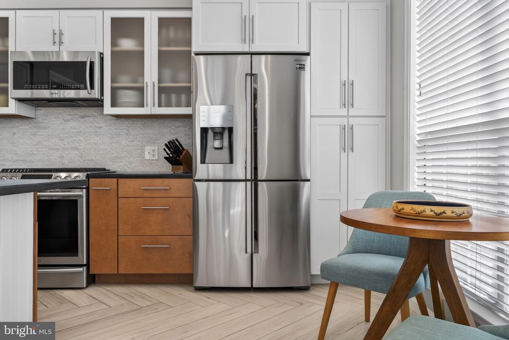 Bright kitchen with stainless steel appliances, white cabinetry, and a small dining nook.