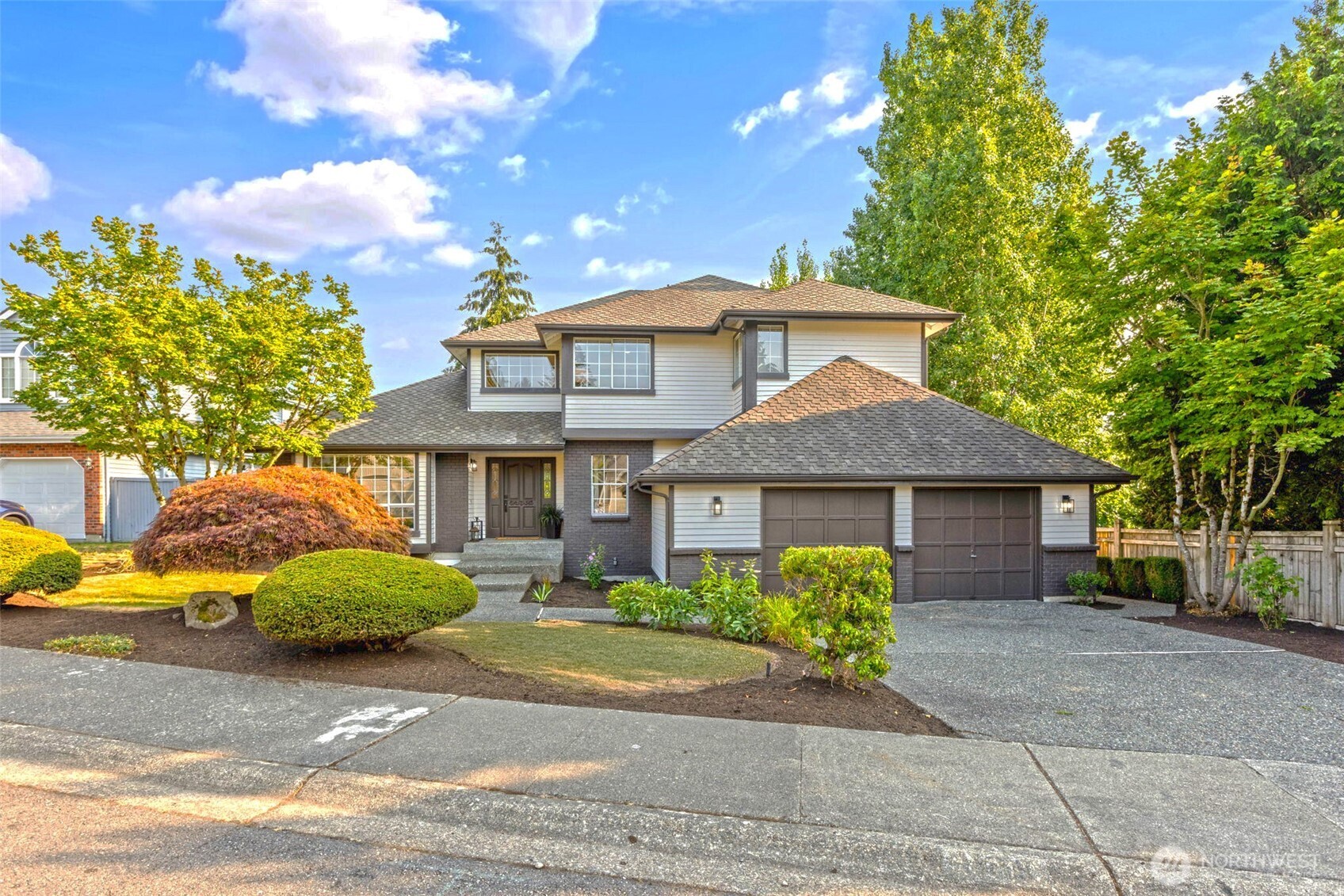 Two-story gray-sided house with brick accents, a two-car garage, and landscaped front yard.