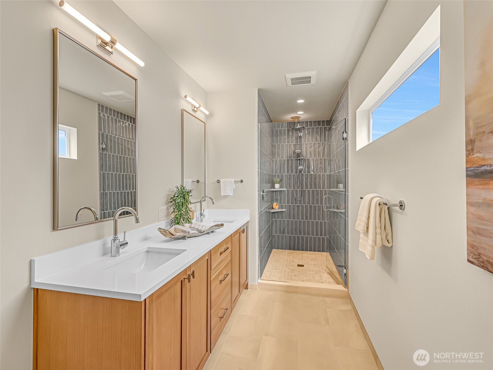 Bathroom with a long wood vanity and a spacious gray-tiled walk-in shower.