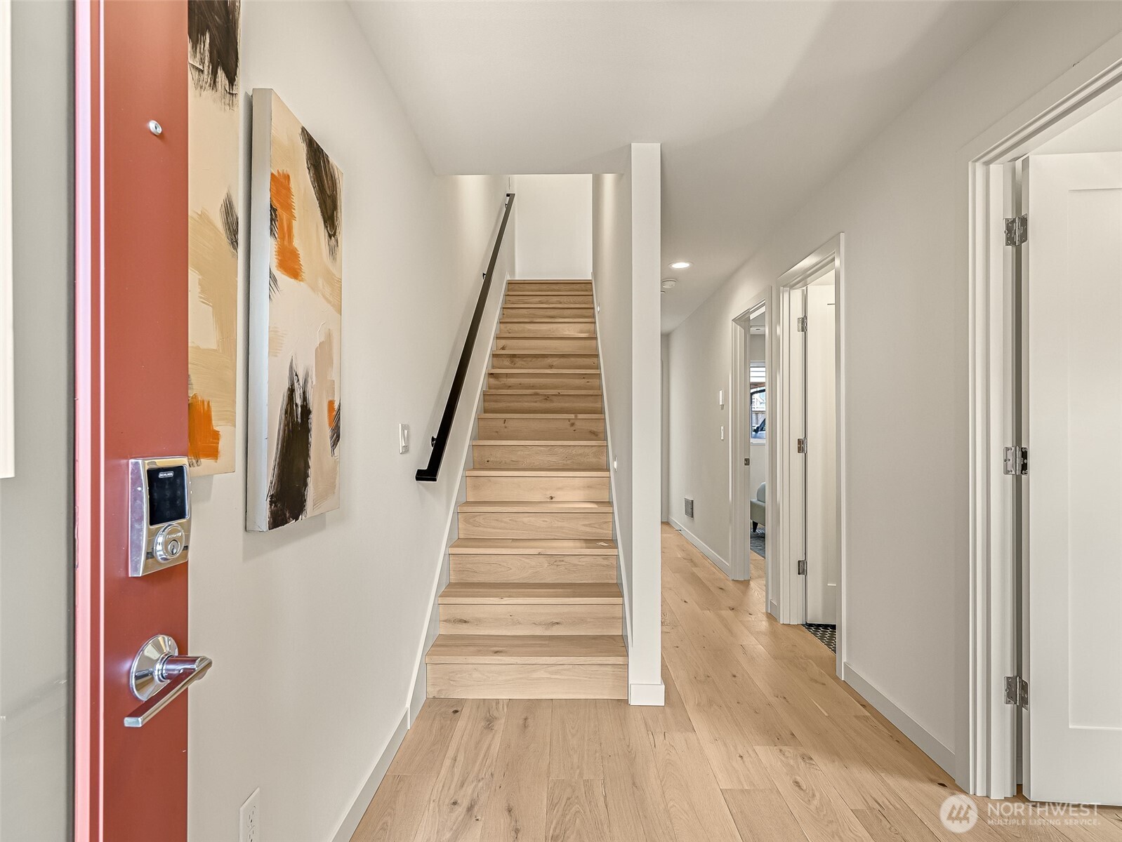 Bright entry hall with a red front door, light oak stairs, and hardwood floors.