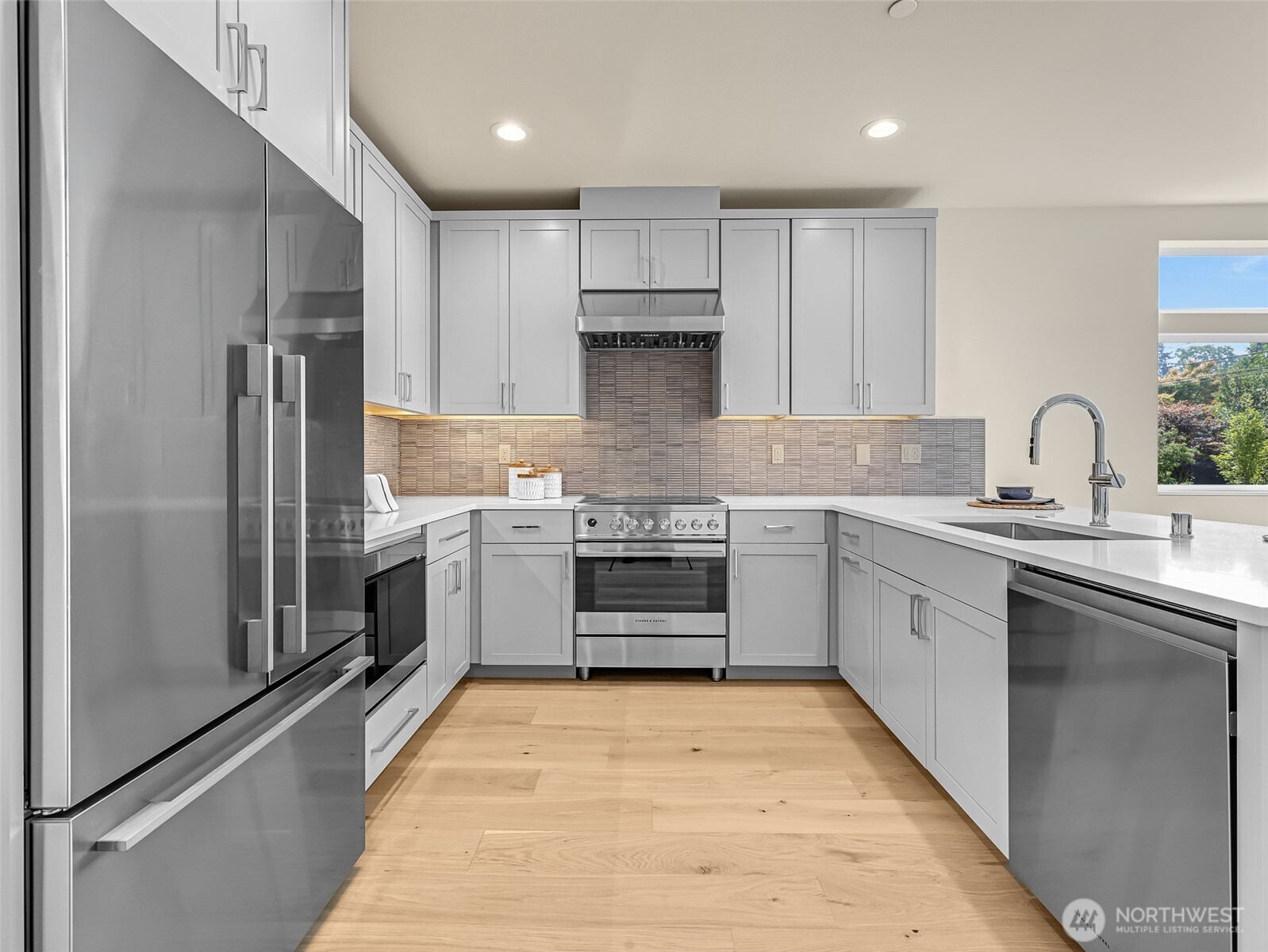 Modern kitchen with white cabinetry, stainless appliances, and a large island sink.