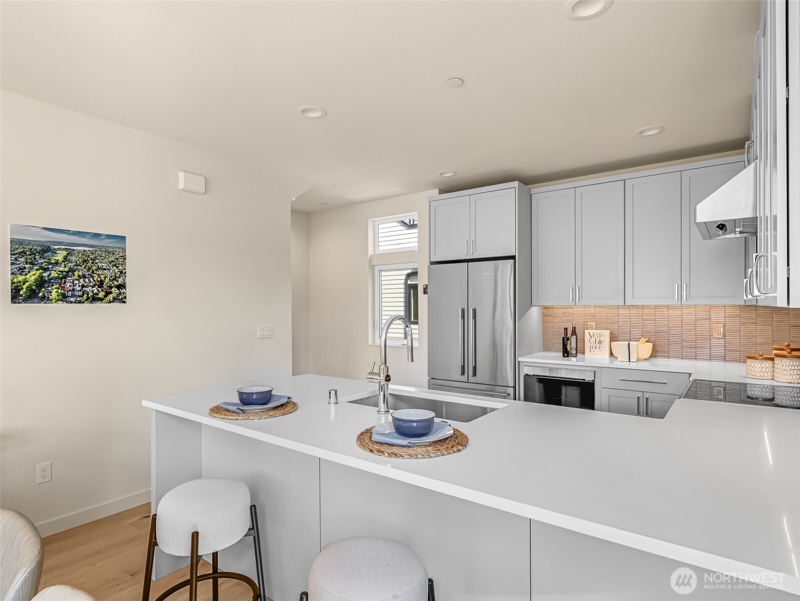 Staged kitchen with white cabinetry, stainless steel appliances, and a large island with sink.