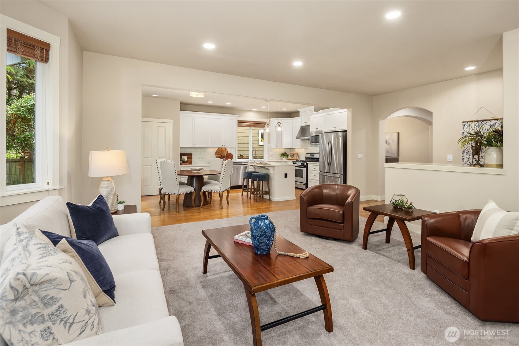 Open-plan living room with leather chairs and a view into the white kitchen.