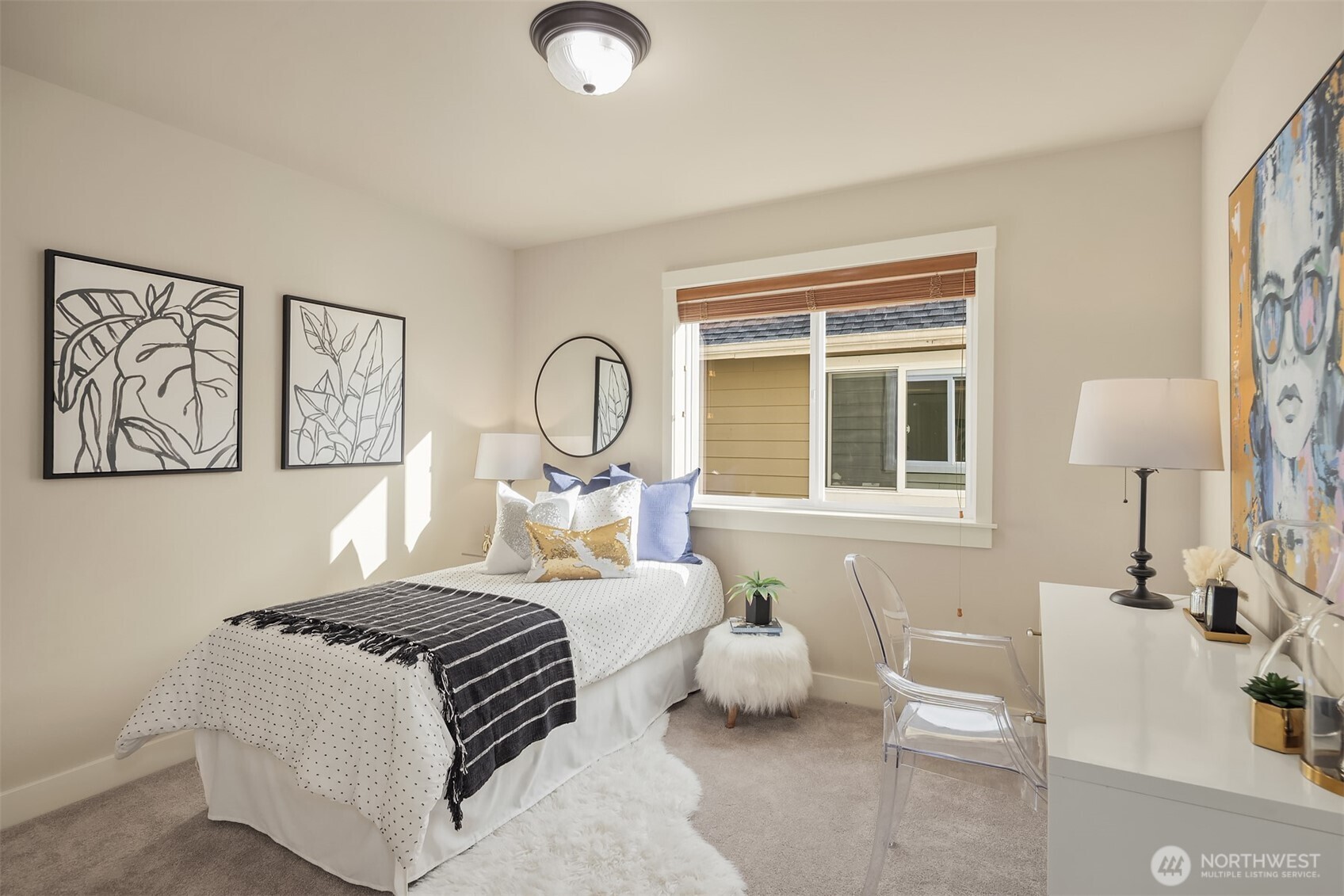 Staged bedroom with a white bed, botanical wall art, and a desk beside the window.