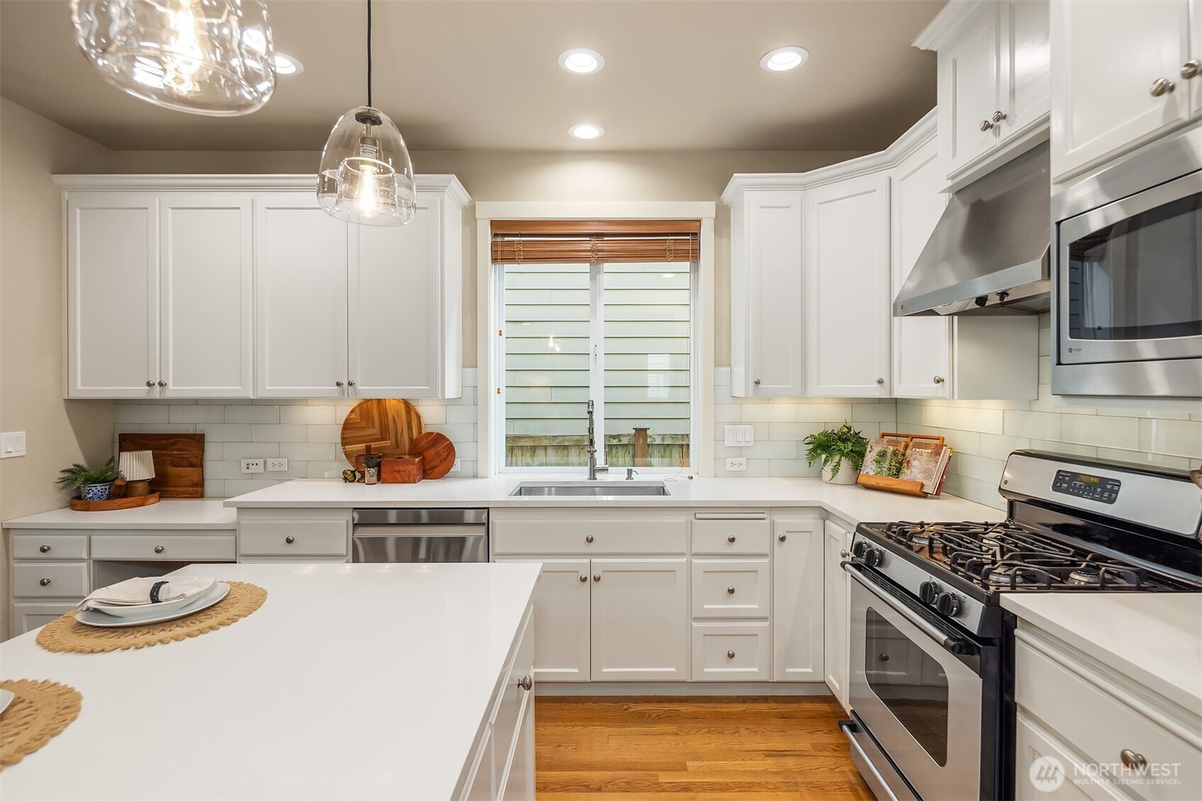 Kitchen with white cabinetry, a large island, stainless steel appliances, and hardwood floors.