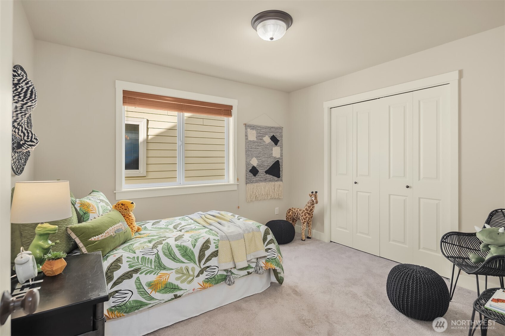 Furnished bedroom with botanical bedding, white closet doors, and animal-themed decor.