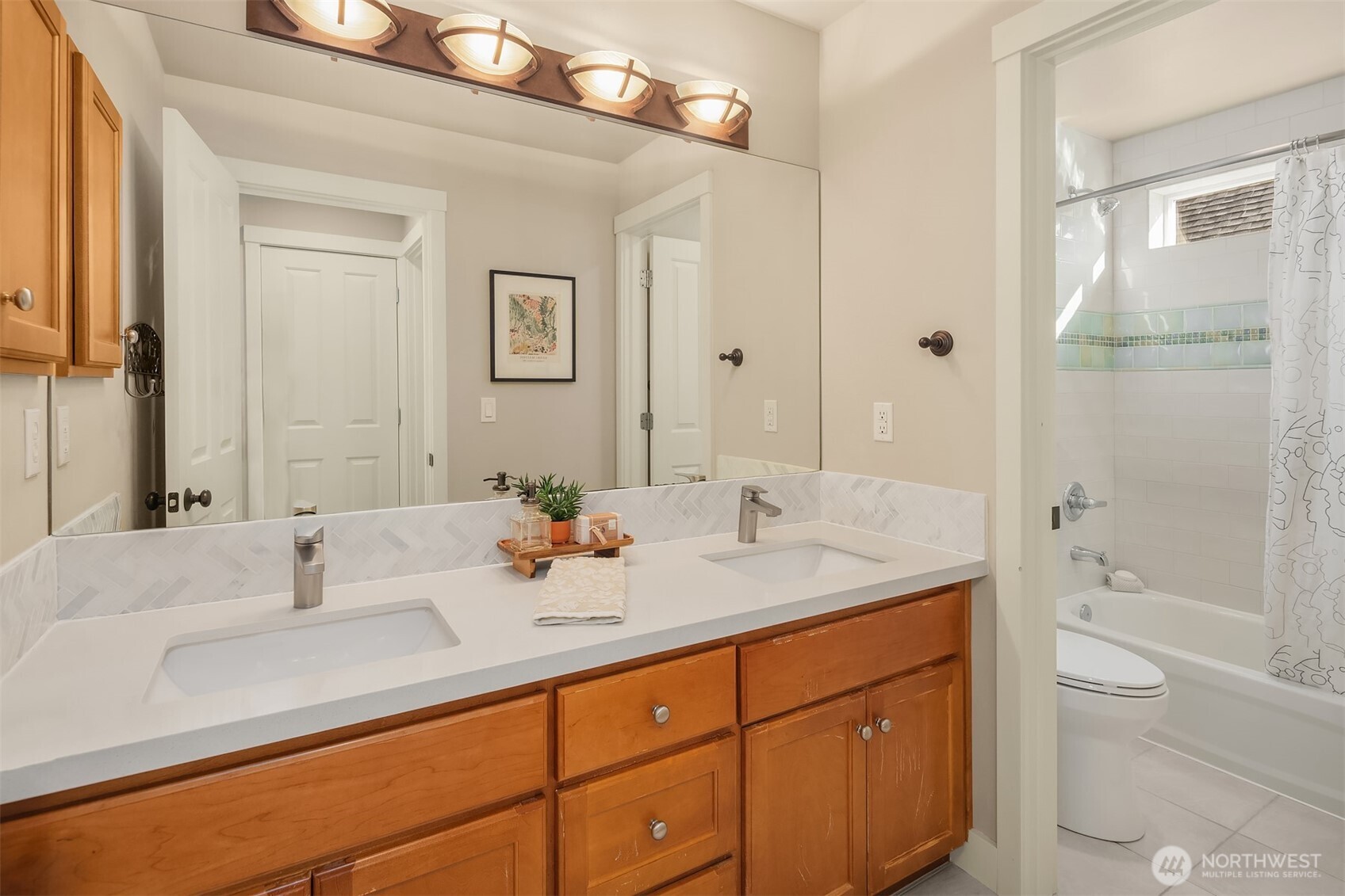 Bathroom with a double-sink wood vanity and an adjoining white-tiled tub and shower.