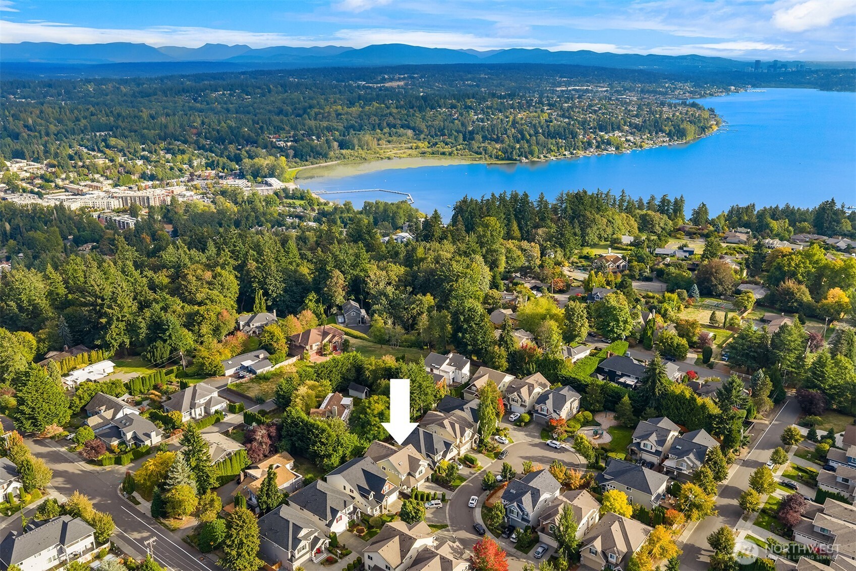 Aerial view of the marked Kirkland home, with a bay and mountain range beyond the neighborhood.