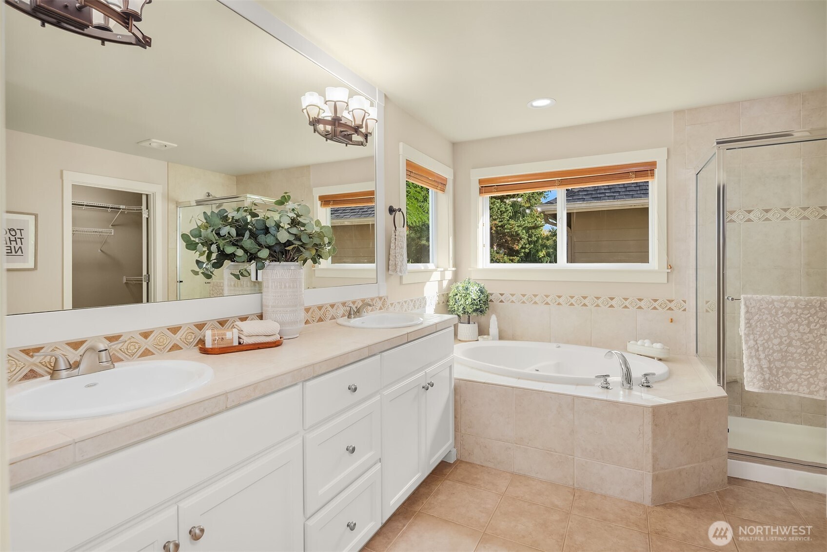 Primary bathroom with a double vanity, corner soaking tub, and glass-enclosed shower.