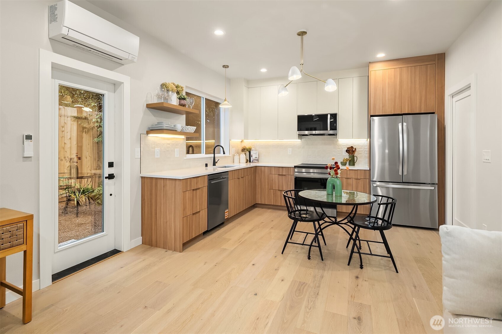 Modern kitchen with wood cabinetry, stainless steel appliances, and a round dining table.