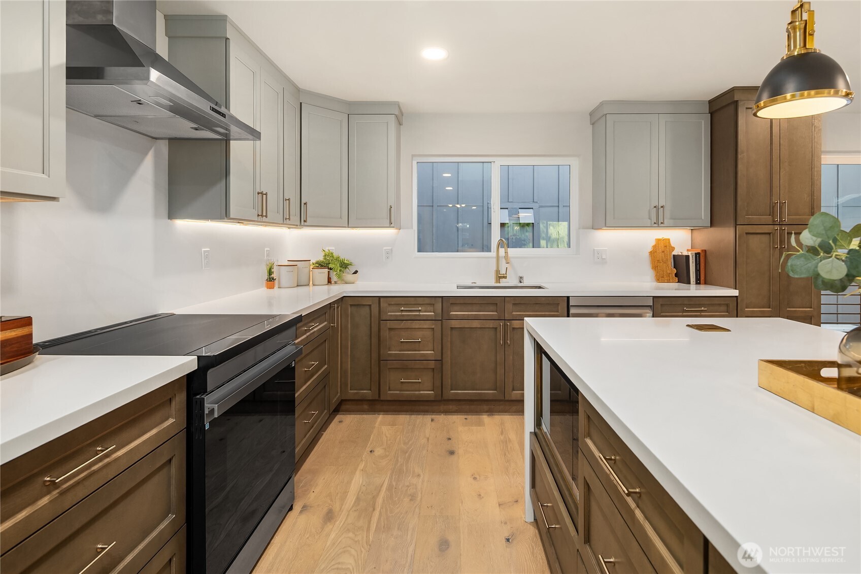 Updated kitchen with two-tone cabinetry, white countertops, a large island, and light wood floors.