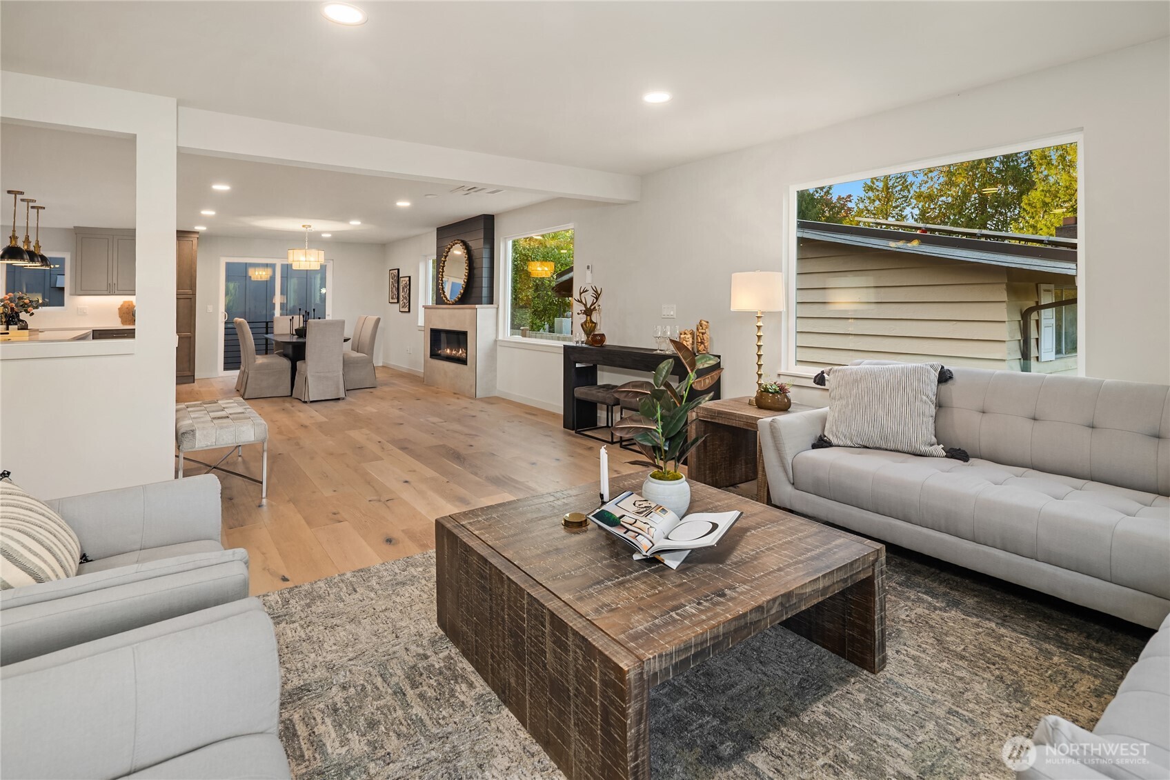 Open-plan living room with gray sofas, a wood coffee table, and a fireplace beside the dining area.