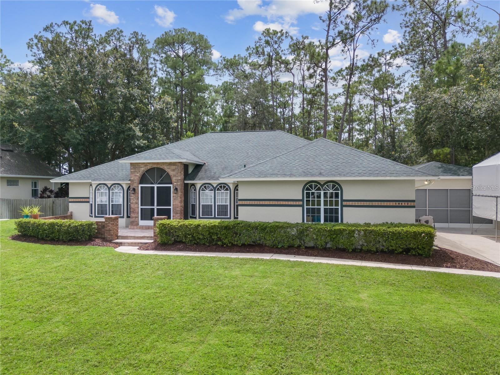 Single-story house with arched windows, brick accents, and a wide green lawn.