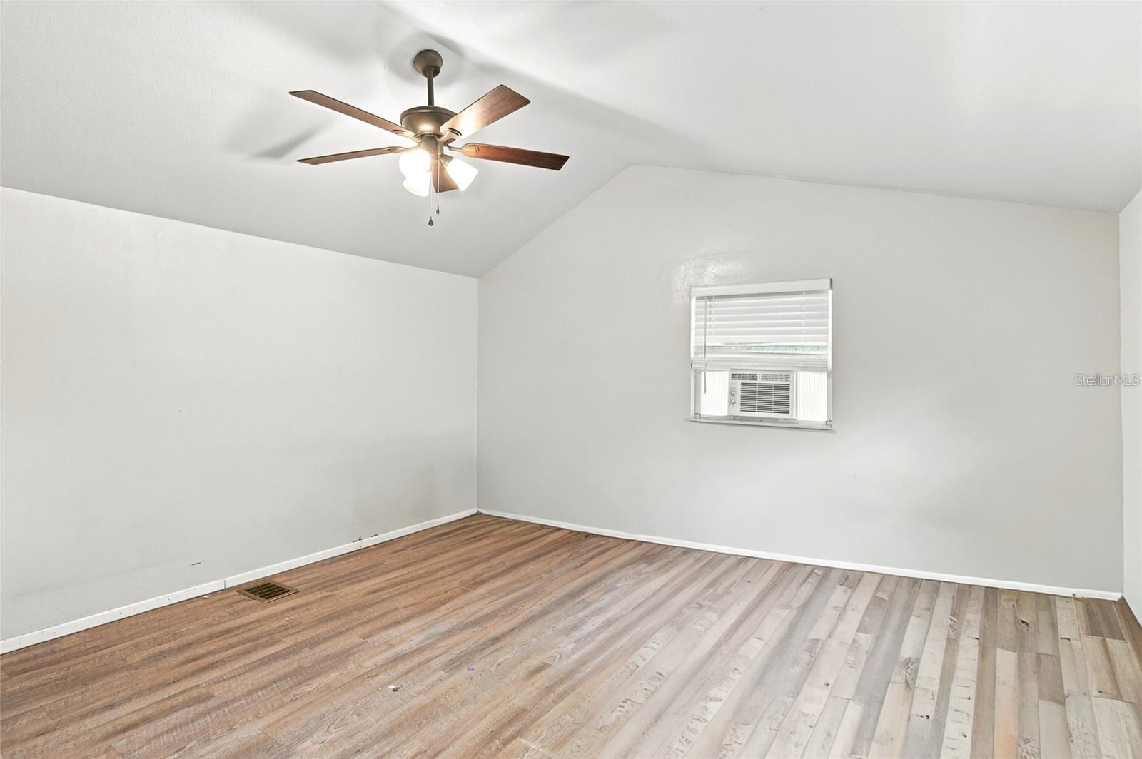 Empty room with wood-look flooring, a ceiling fan, and a window air conditioner.