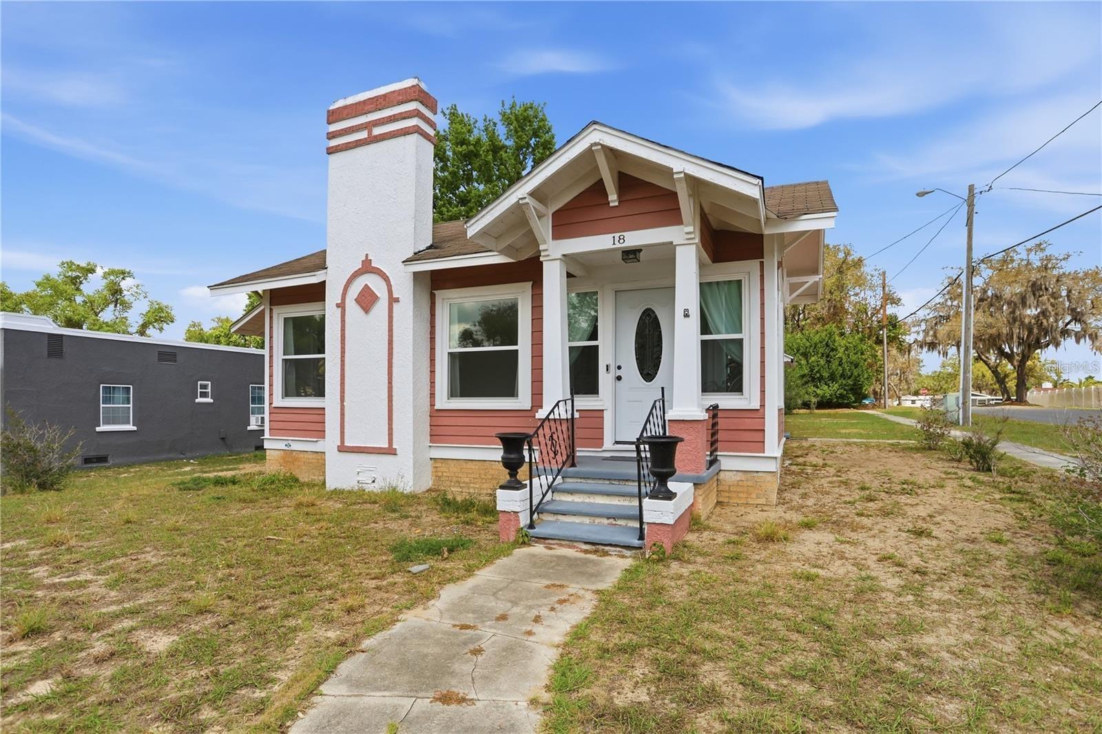 Coral-pink house with white trim, a tall chimney, and covered porch above the front steps.