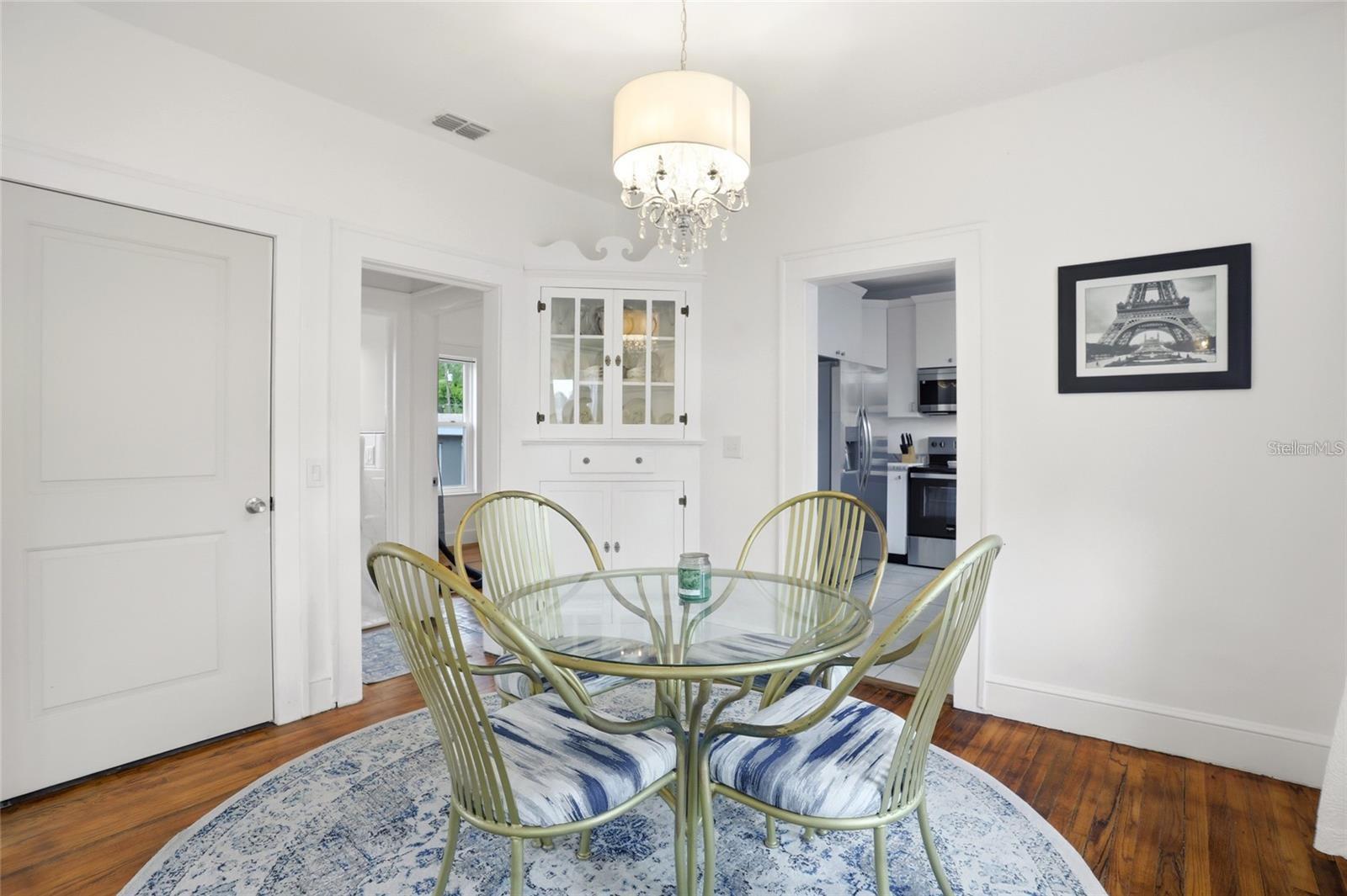 Dining room with a glass-top table, green chairs, built-in cabinet, and doorway to the kitchen.