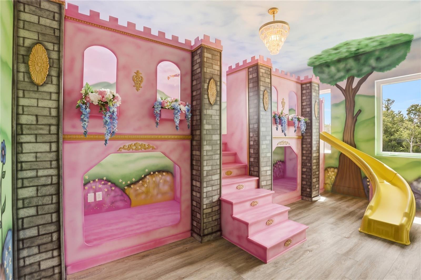 Castle-themed playroom with pink built-ins, a yellow slide, and a painted tree mural.