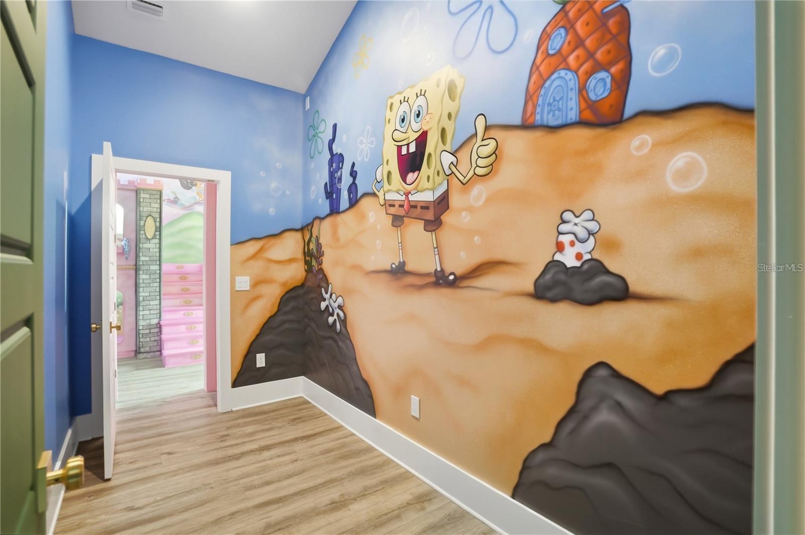 Themed bedroom with a SpongeBob mural and doorway to a pink room.