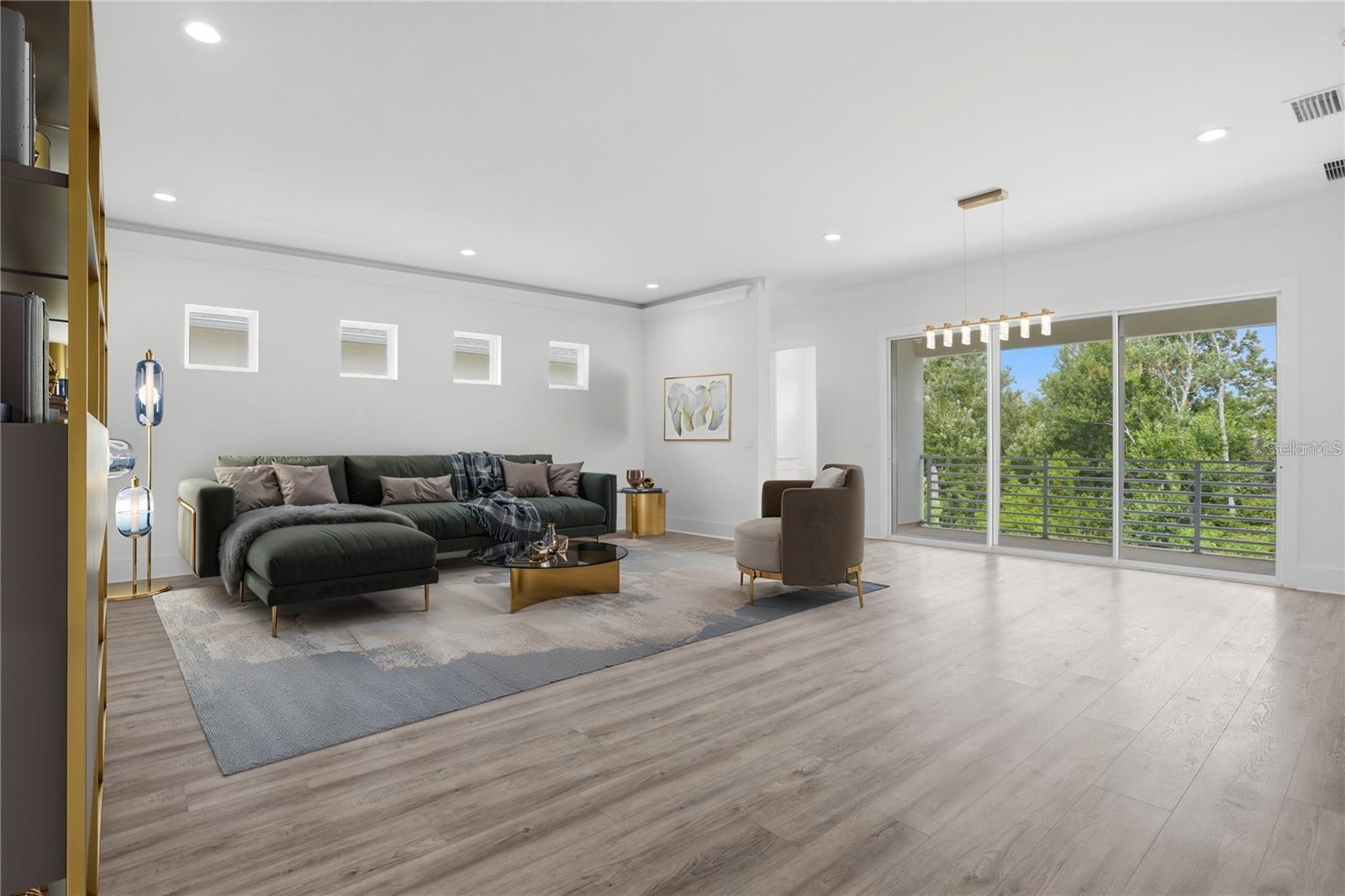 Staged living room with a dark sectional and sliding doors overlooking trees and a balcony.