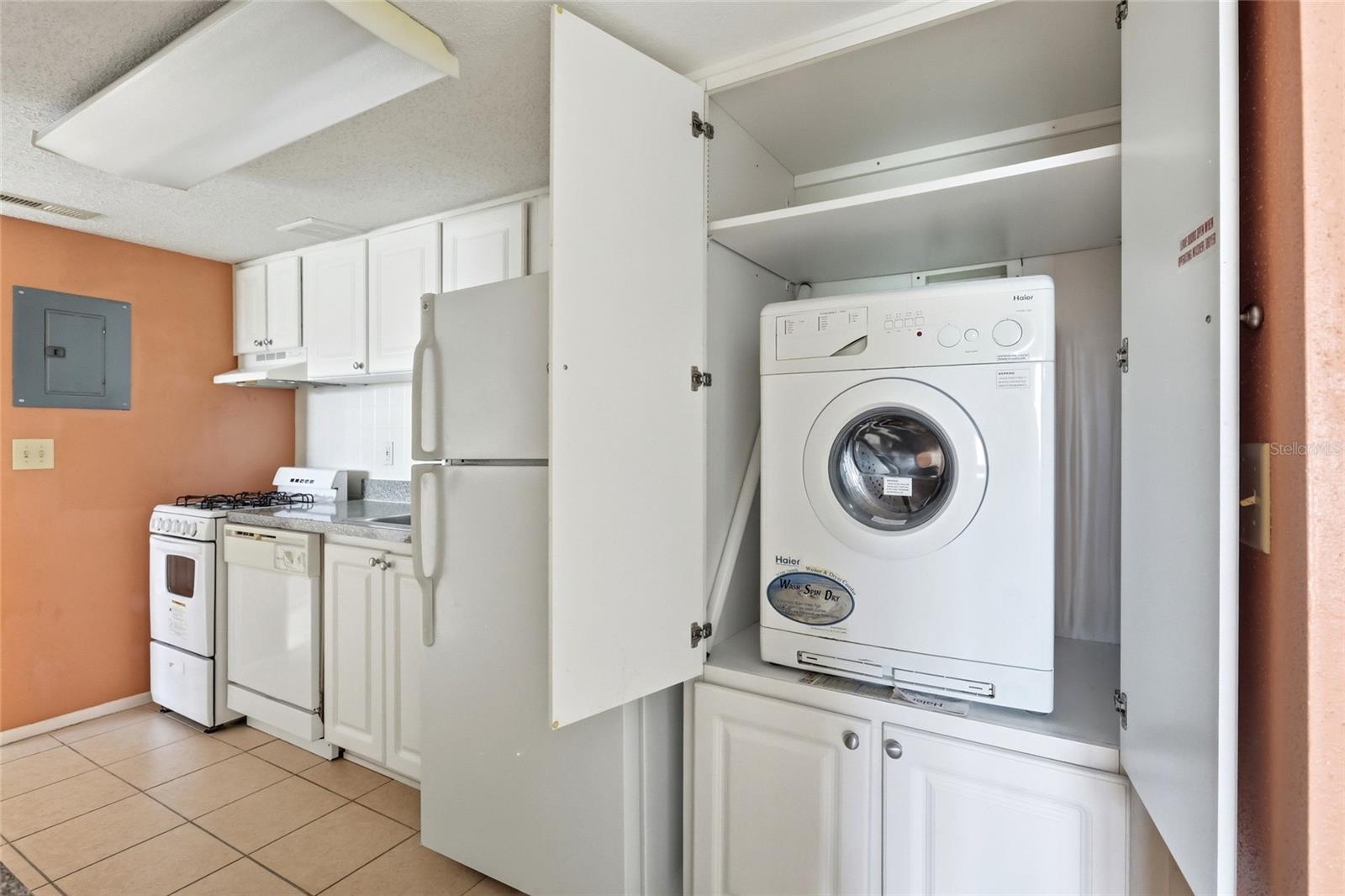 Kitchen with a front-loading washer-dryer tucked beside the refrigerator and gas range.