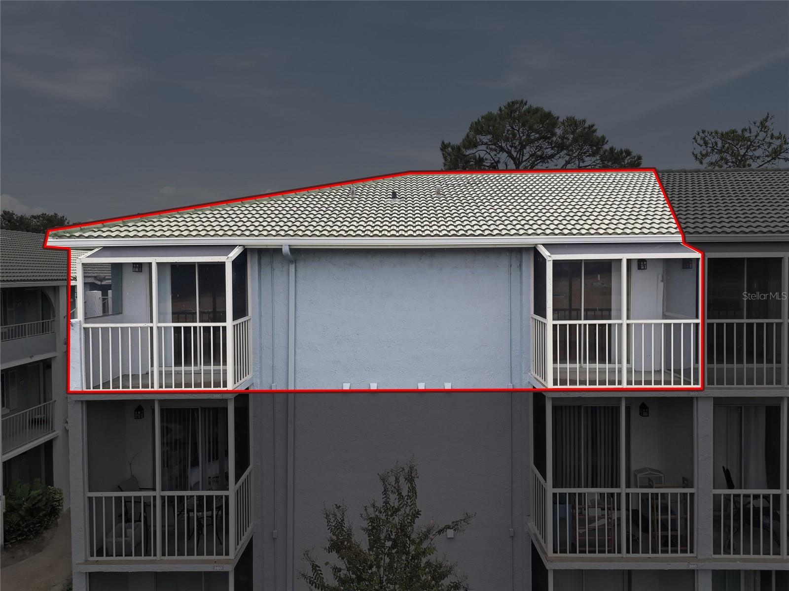 Upper-floor condominium unit outlined in red, with two screened balconies and a tiled roof.