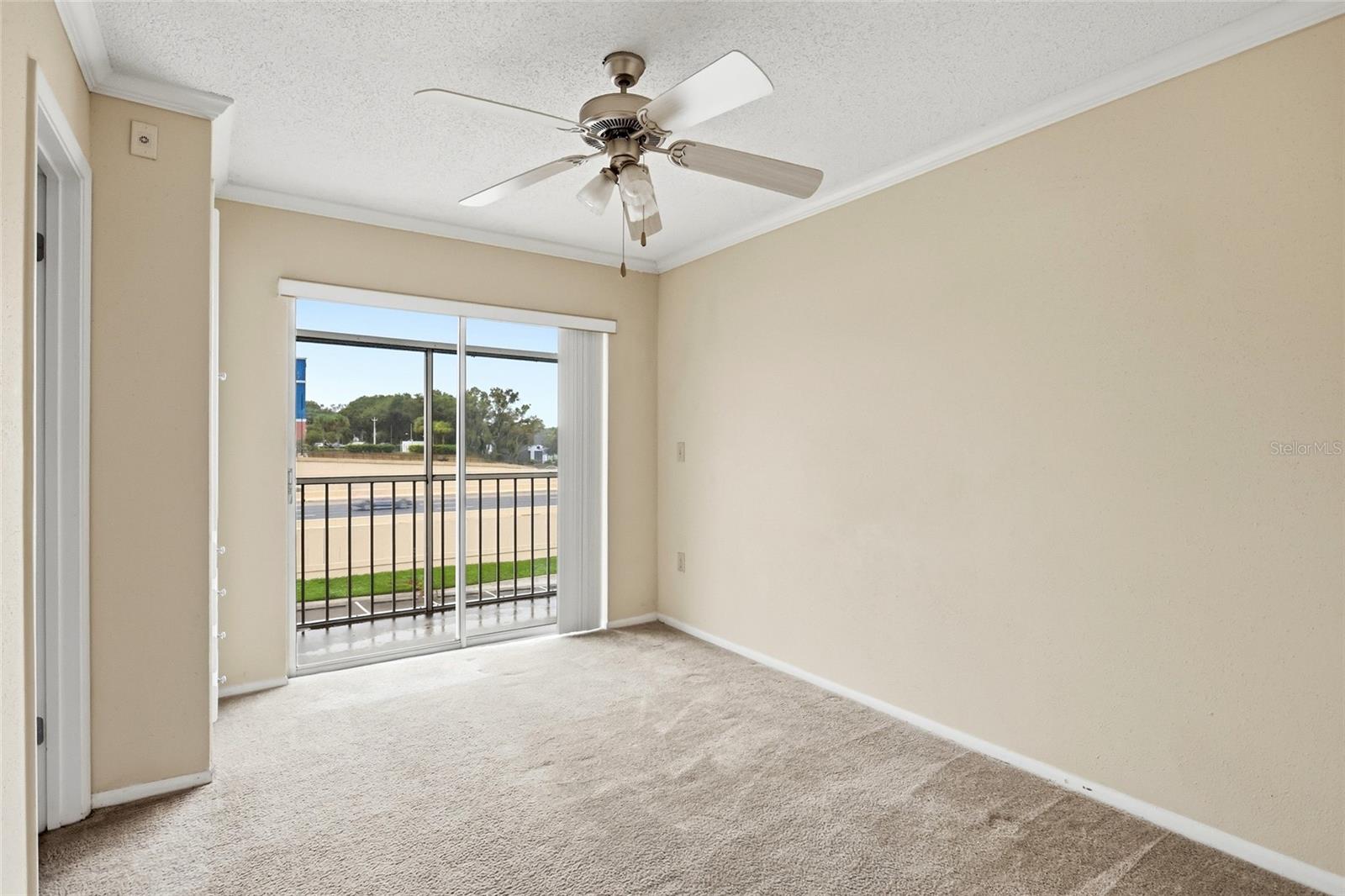Unfurnished carpeted bedroom with a ceiling fan and sliding glass door to a balcony.