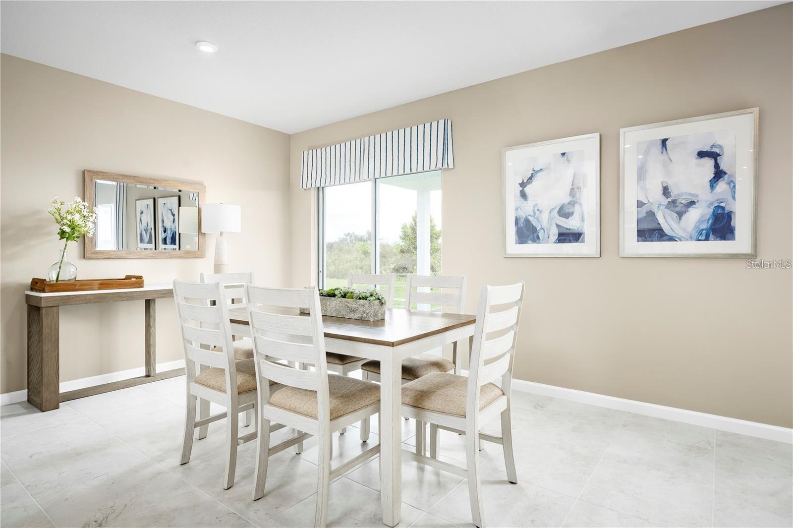 Dining room with white table and chairs beside a large sliding glass door.