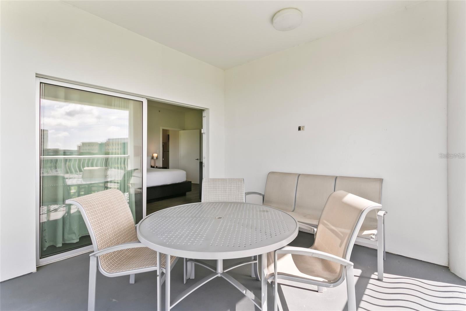 Covered patio with a round table and chairs beside a sliding glass door.