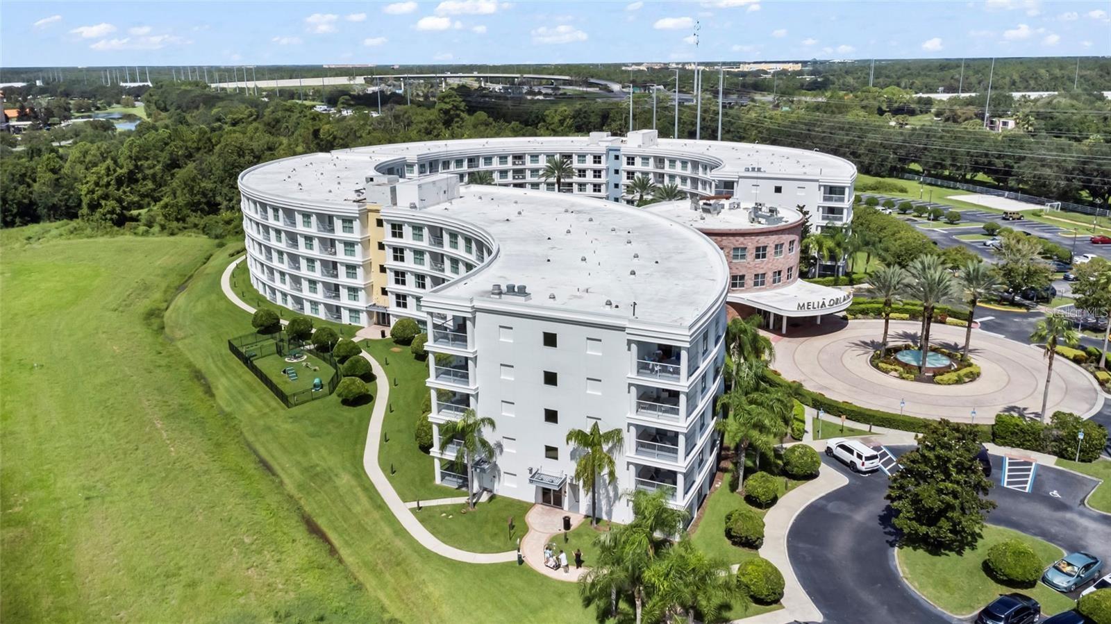 Curved multi-story hotel with landscaped grounds and a circular entrance drive.