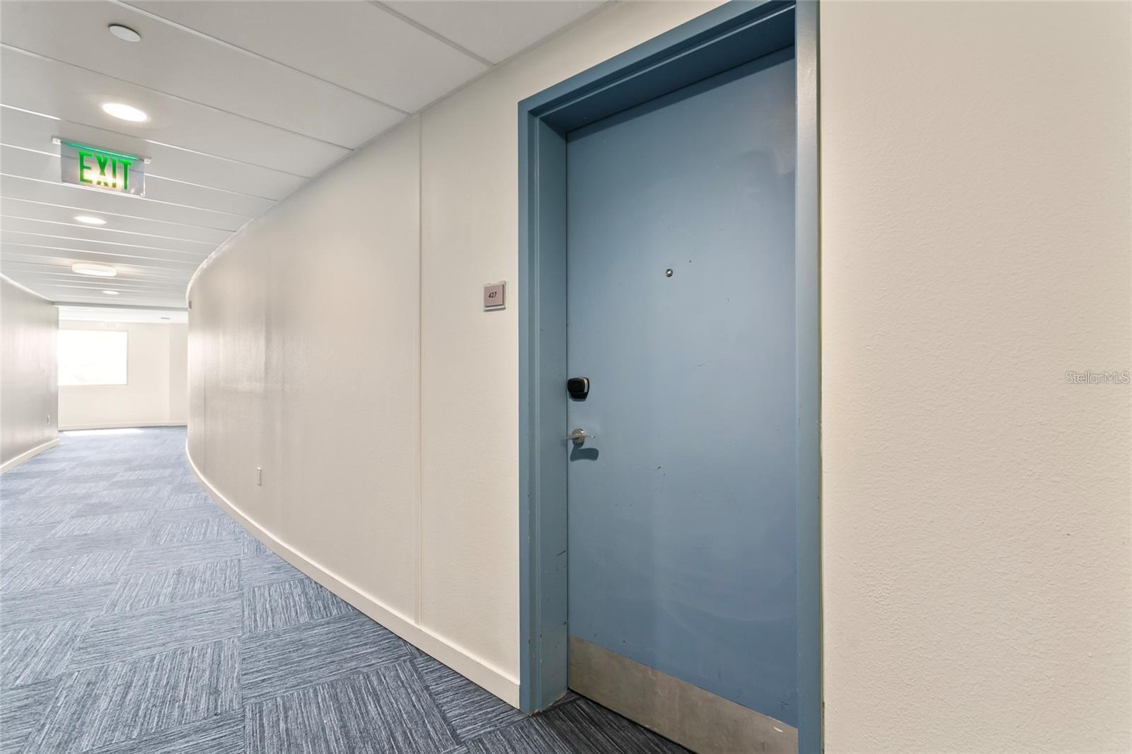 Condominium hallway with blue carpet and a blue door marked 427.