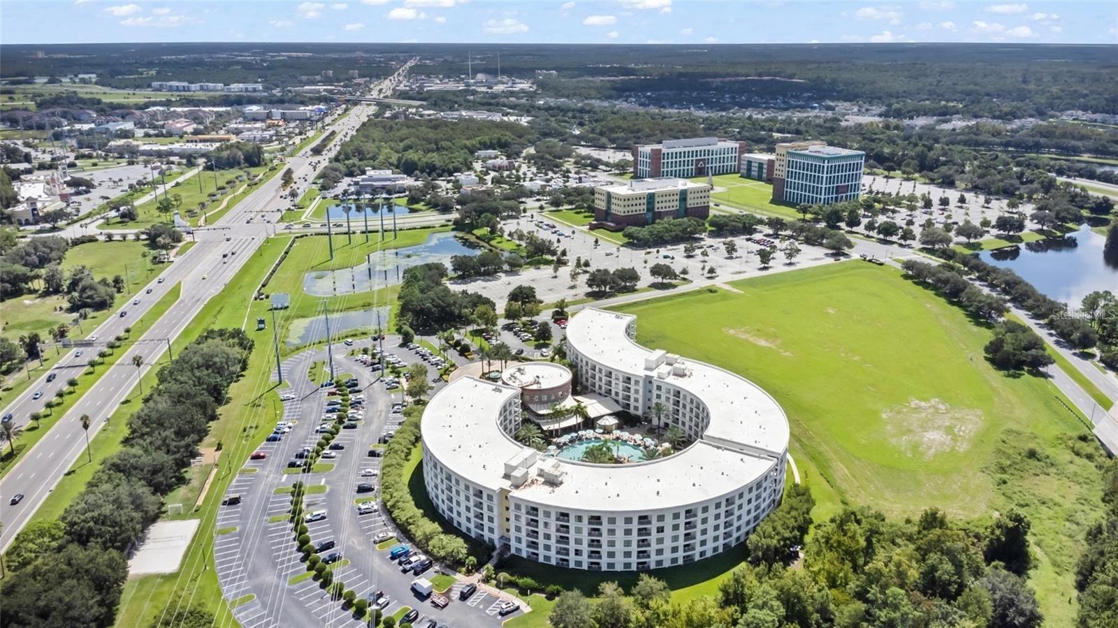 Aerial view of a circular white building with a landscaped courtyard and pool.