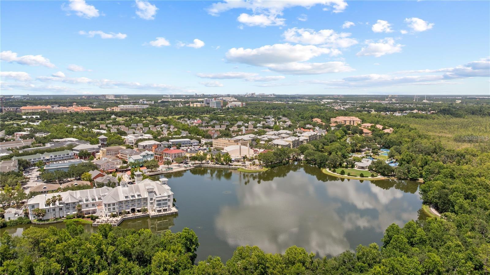 Aerial view of a lakeside community with waterfront buildings and a tree-lined lake.
