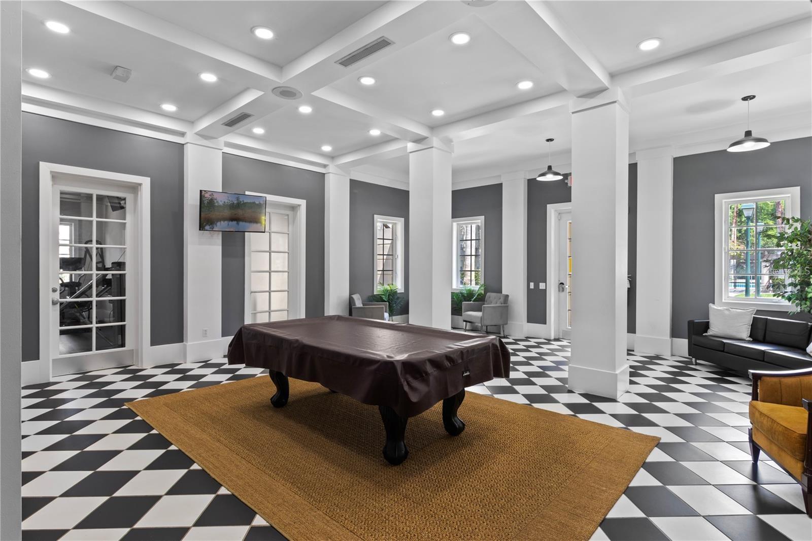Community recreation room with a covered pool table, checkerboard floor, and seating.