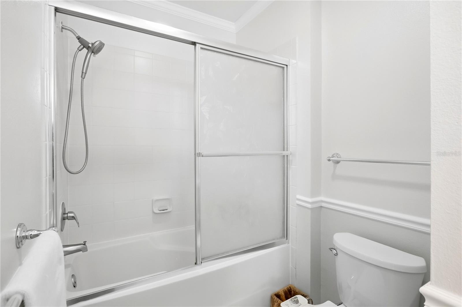 Bathroom with a white tub, frosted sliding shower doors, and toilet.