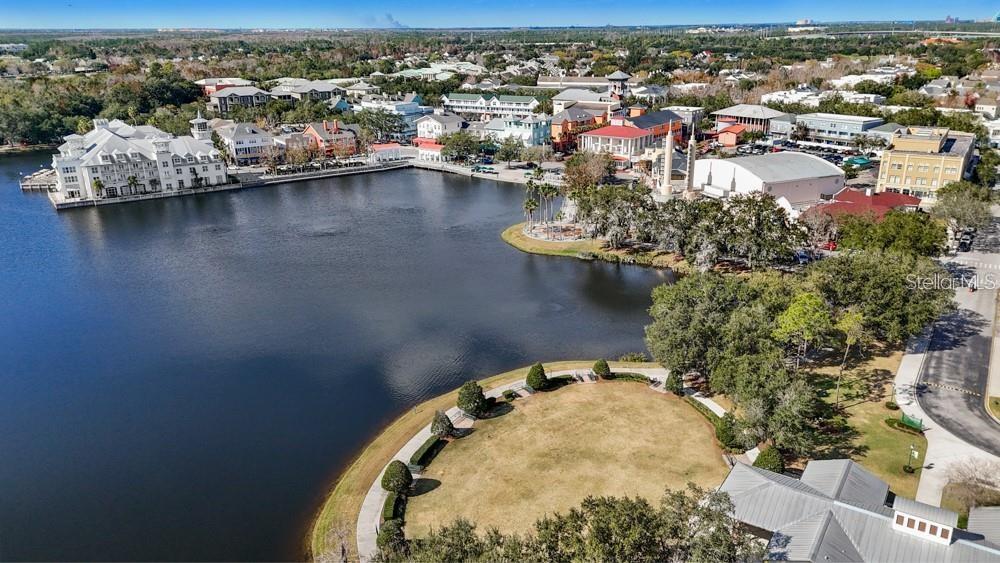 Aerial view of a lakefront town center with waterfront buildings and a curved grassy shoreline.