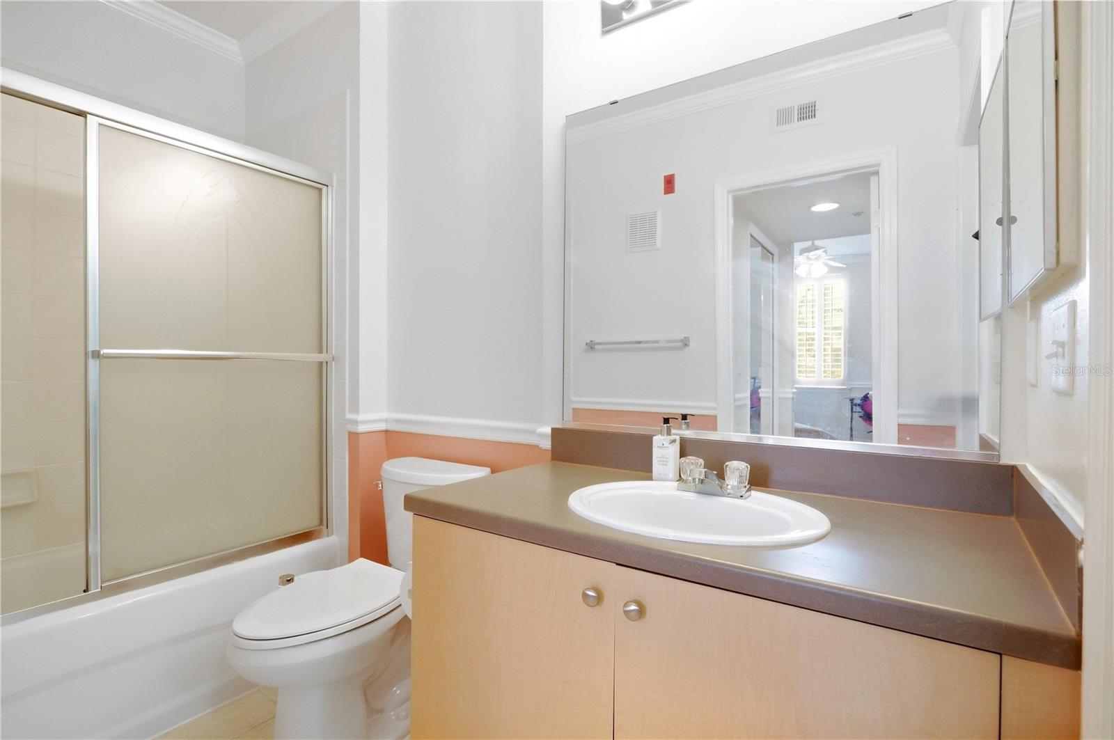 Bathroom with a tub and frosted sliding doors beside a single-sink vanity.