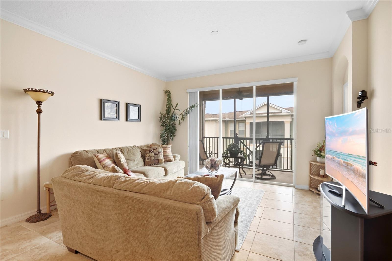 Living room with a beige sectional sofa and sliding glass doors opening onto a covered balcony.