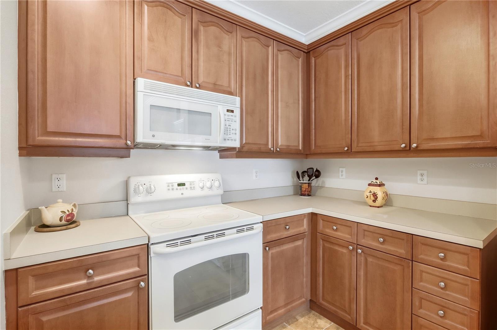Kitchen with wood cabinets, light countertops, and a white range with microwave.