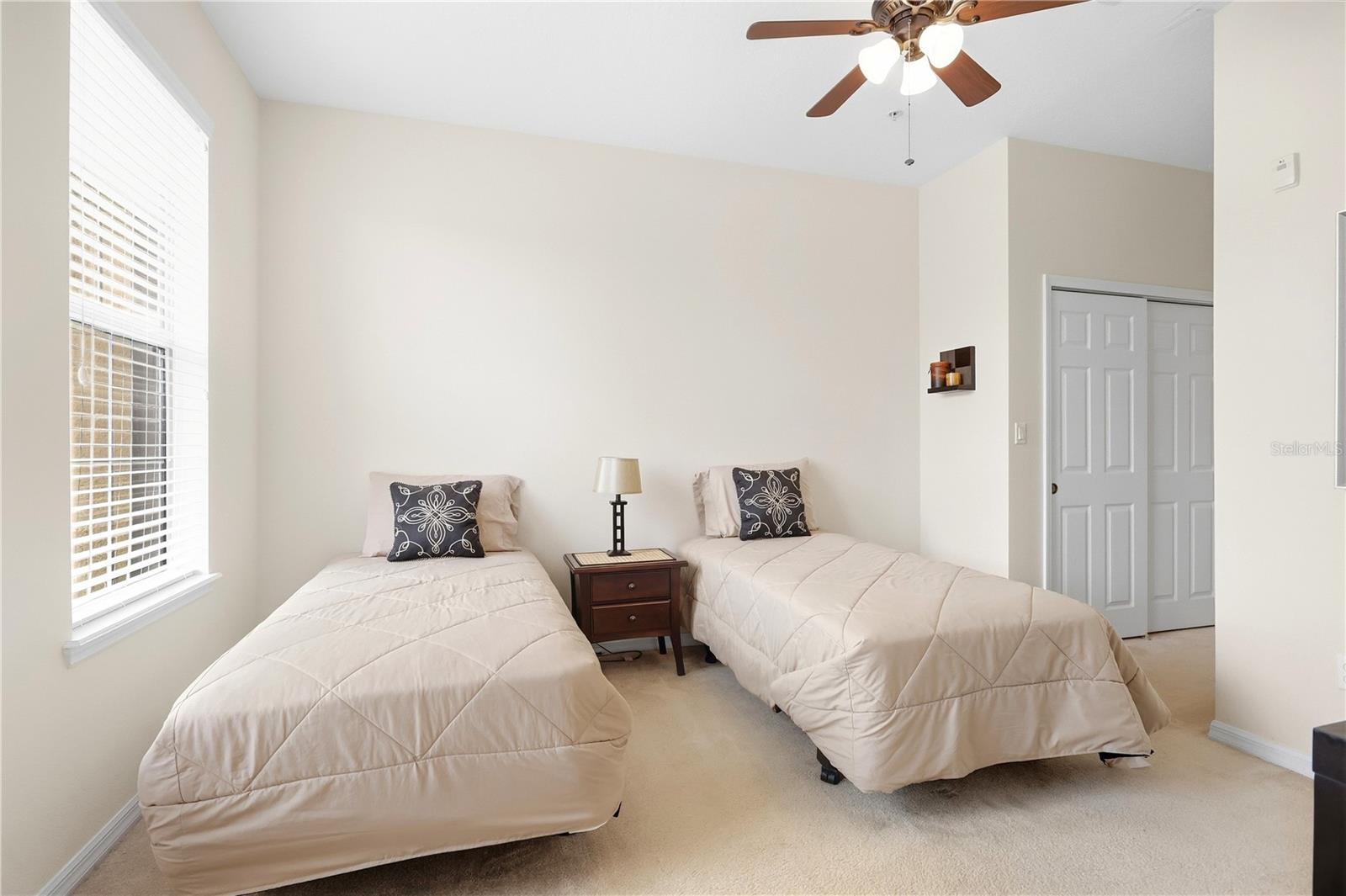 Bedroom with two single beds, a nightstand between them, and a ceiling fan.