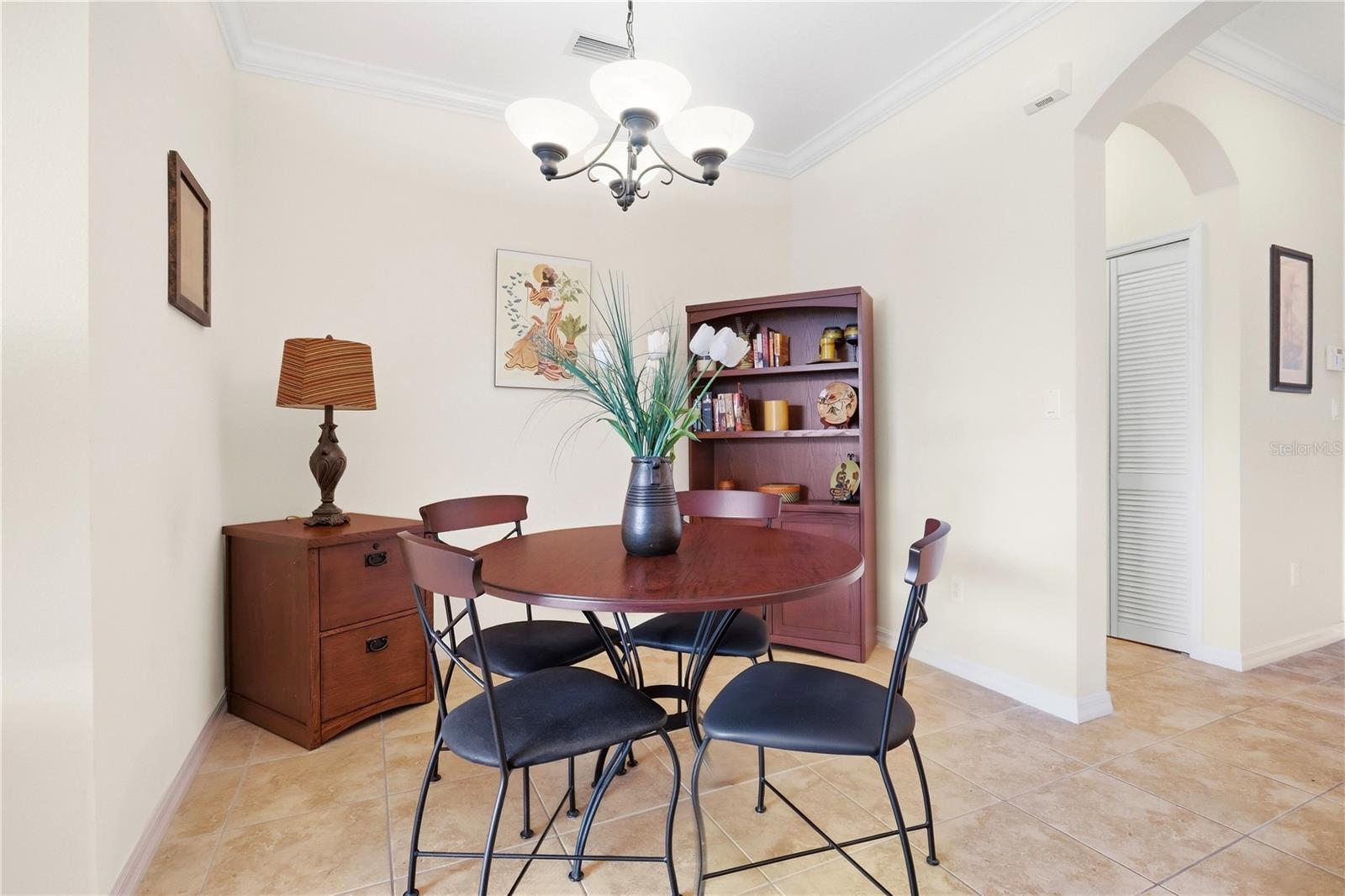 Dining area with a round wooden table, black chairs, and a bookcase.