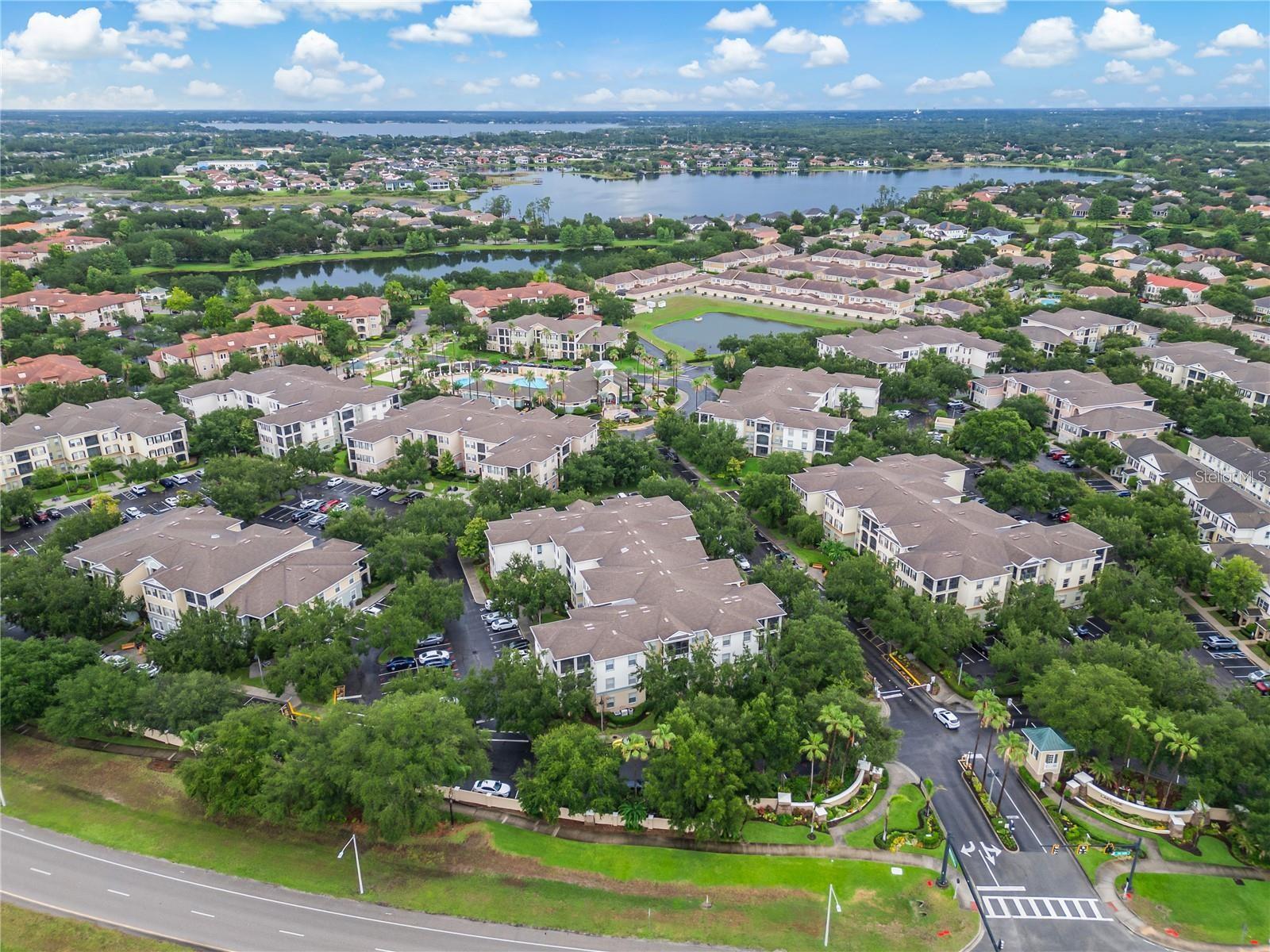 Aerial view of a condominium community surrounded by trees, with several lakes in the distance.
